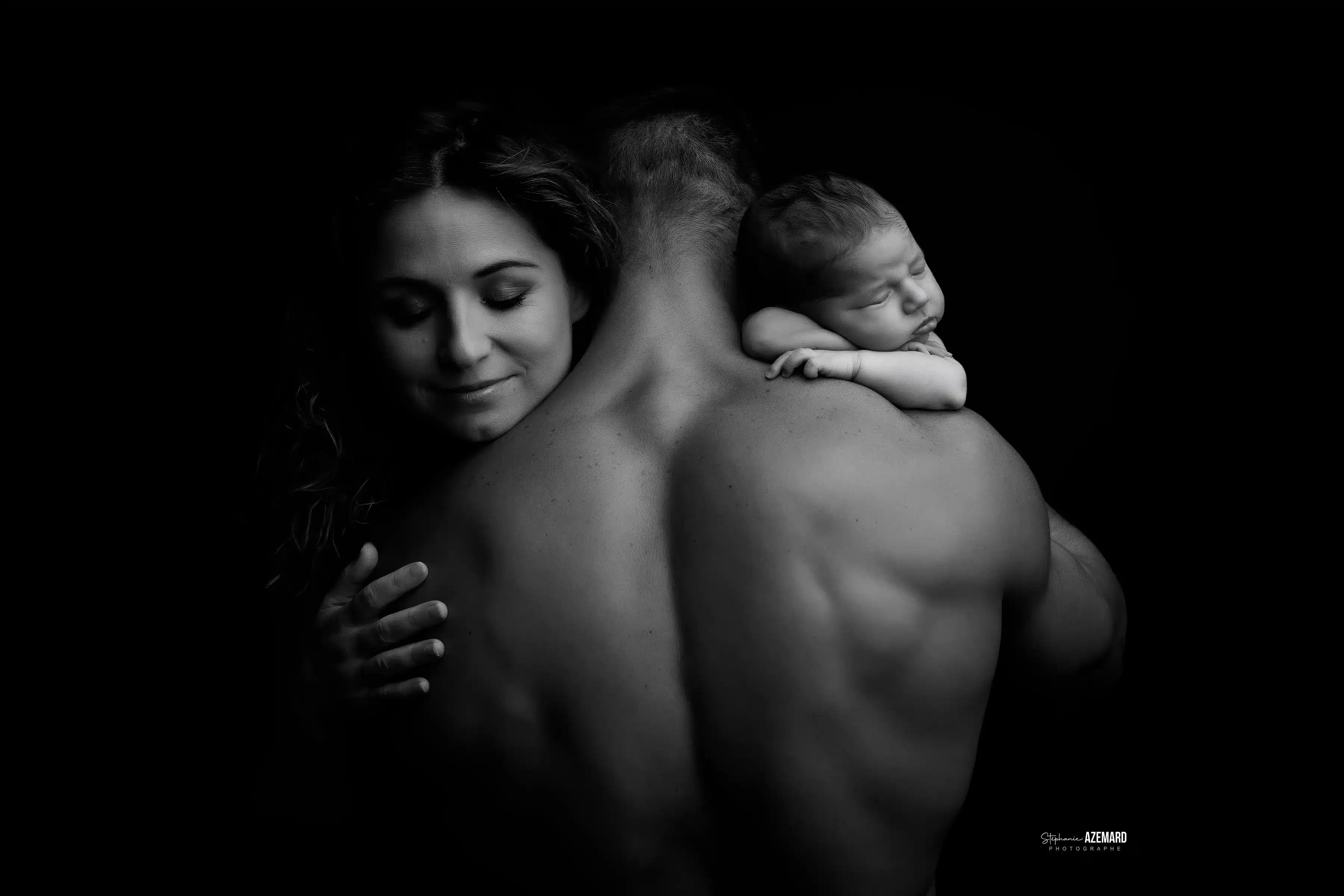 Séance photo nouveau-né famille noir et blanc studio — bébé endormi sur le dos de papa, maman complice — Stéphanie Azémard photographe maternité Montpellier