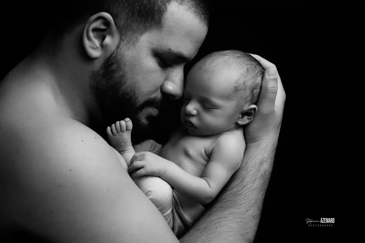 Photo nouveau-né endormi contre la joue de son papa en noir et blanc studio, photographe maternité Montpellier Stéphanie Azémard