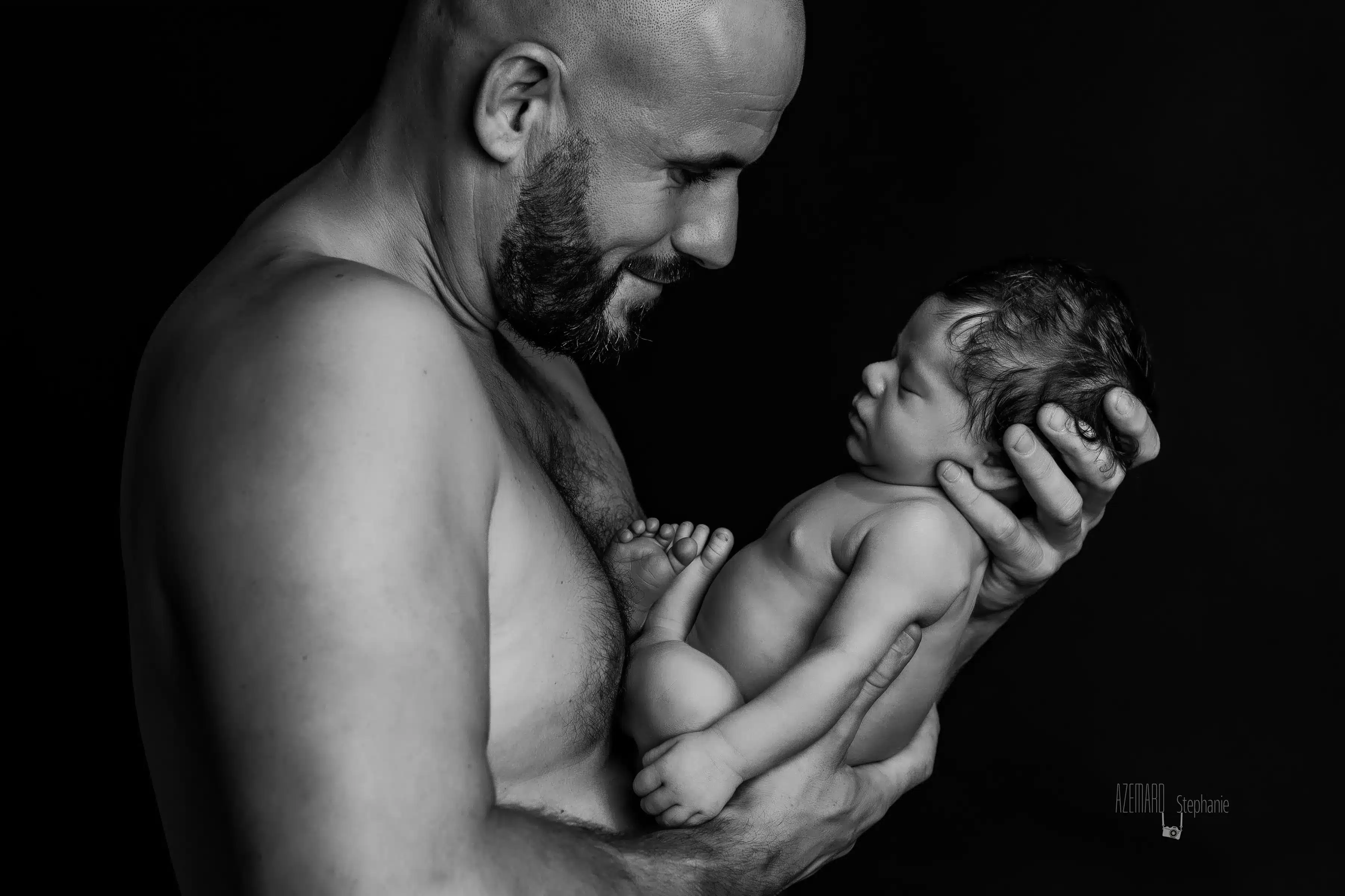 Séance photo nouveau-né papa souriant bras noir et blanc studio — Stéphanie Azémard photographe maternité Montpellier
