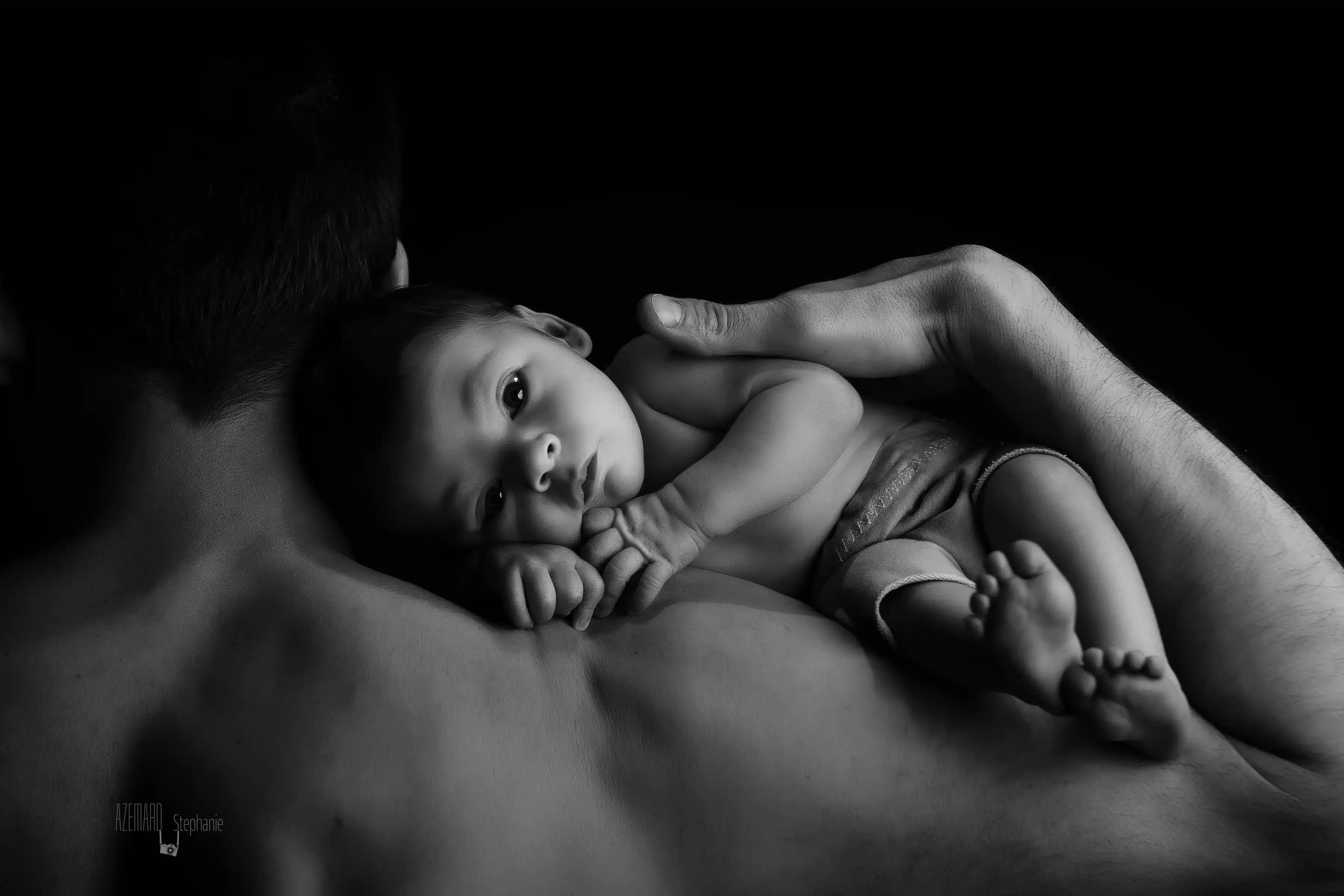 Séance photo nouveau-né peau à peau avec papa noir et blanc — Stéphanie Azémard photographe maternité Montpellier